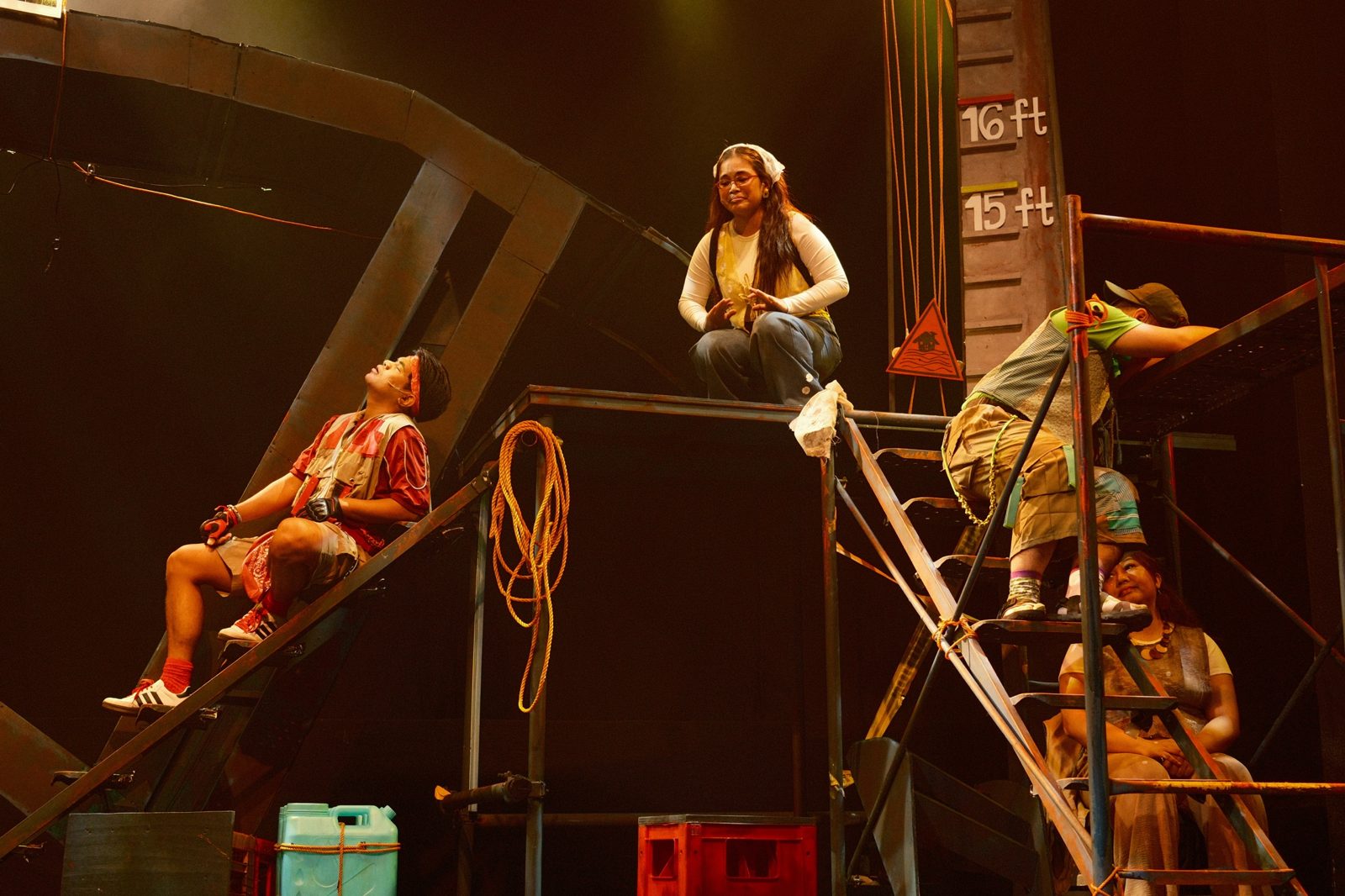 Actors perched across scaffolding beside a flood marker reading 15 and 16 feet