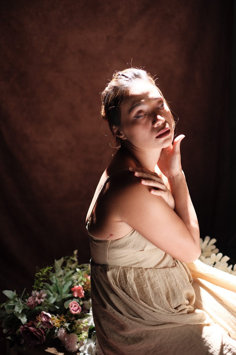 A woman with eyes closed, hand at her throat, face lit by a slice of light